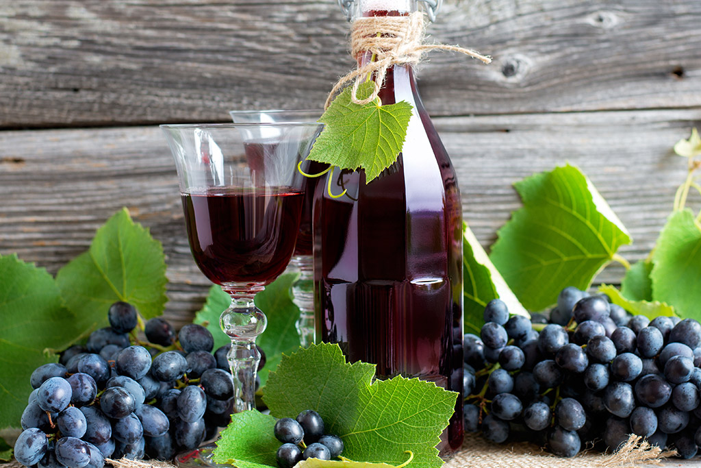 Garrafa de suco de uva integral e taça de vinho.