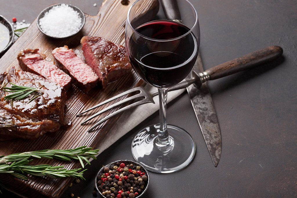 Taninos do vinho: Taça de vinho e tábua de carnes